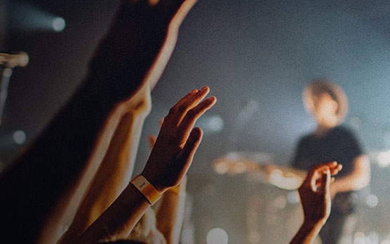 People raising their hands at a live concert, symbolizing community engagement and connection, relevant to building faith communiti