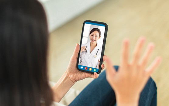 A person using a smartphone for a telemedicine consultation, displaying a h