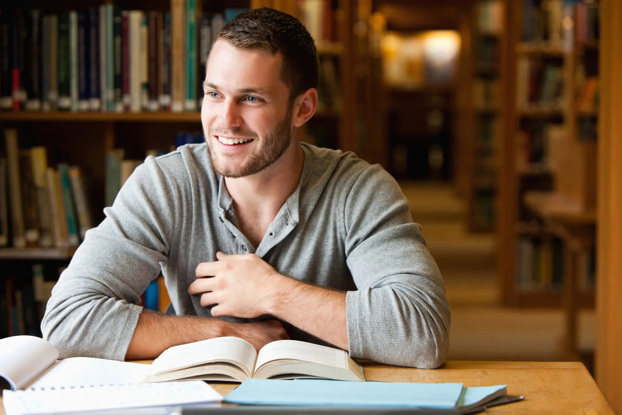 Smiling student studying in a library, representing education and WordPress LMS hosting solutions.